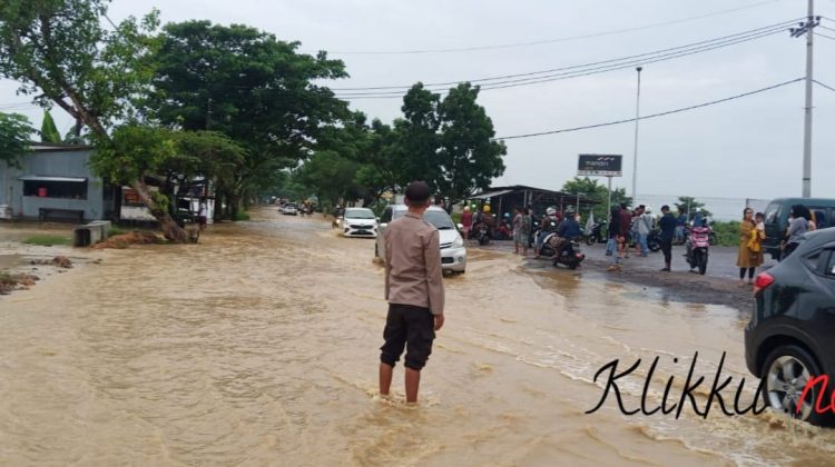 Keterangan Photo : Anggota Polsek Jrengik Mengatur Lalu Lintas di Jalan Raya yang Kebanjiran. Foto : Anaf