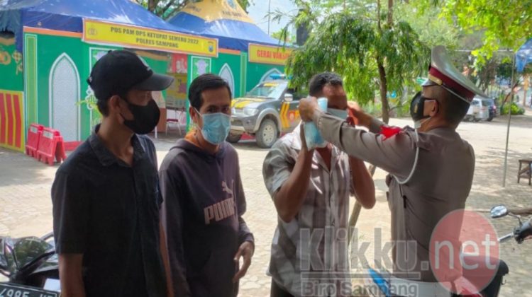 Satlantas Polres Sampang Saat Memasangkan Masker ke Wisatawan Pantai Camplong (Photo : Humas Polres Sampang)